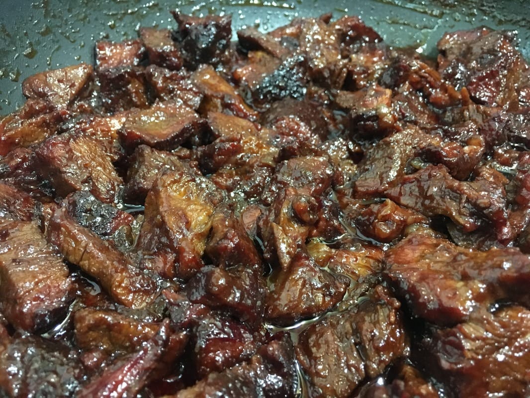 smoked BBQ chuck roast simmering in BBQ sauce for BBQ beef
