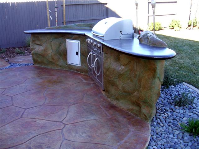 outdoor kitchen BBQ island with polished concrete counter top and stamped stained concrete patio